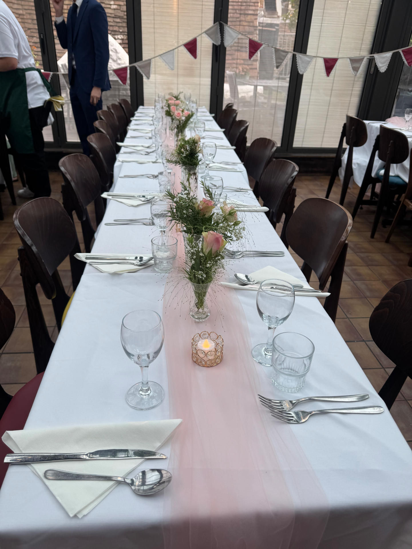 Long reception table with cascading blush florals and taper candles at golden hour