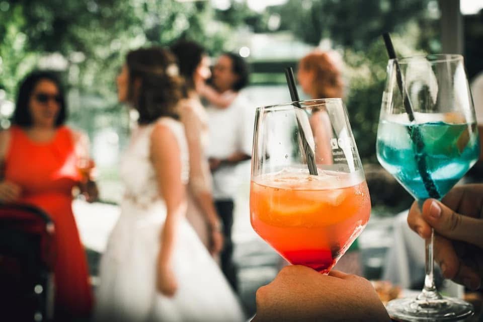 Colourful wedding drinks raised during an outdoor celebration