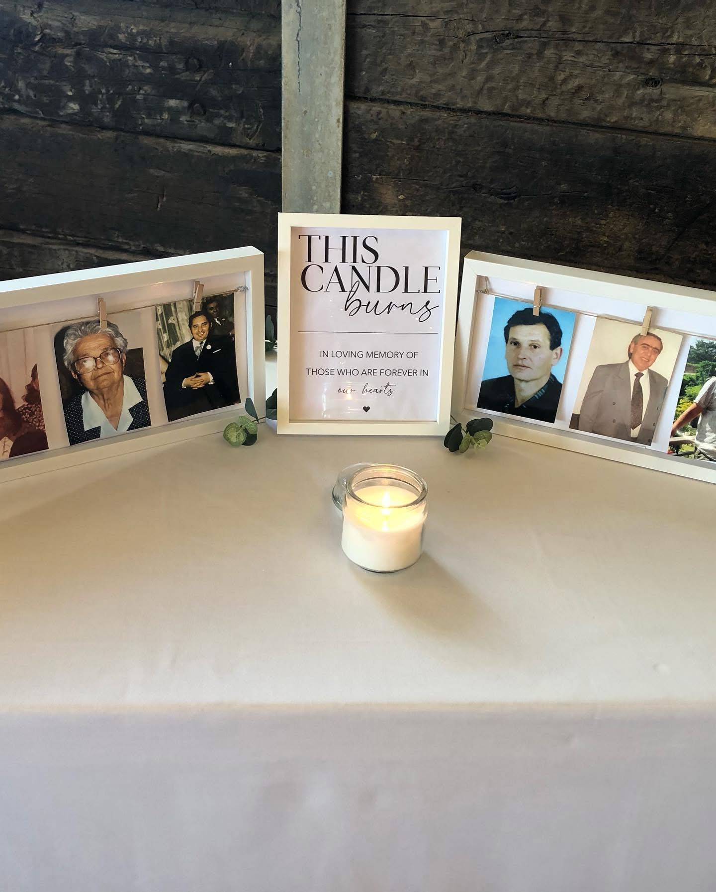 Wedding remembrance table with framed family photographs and a lit candle